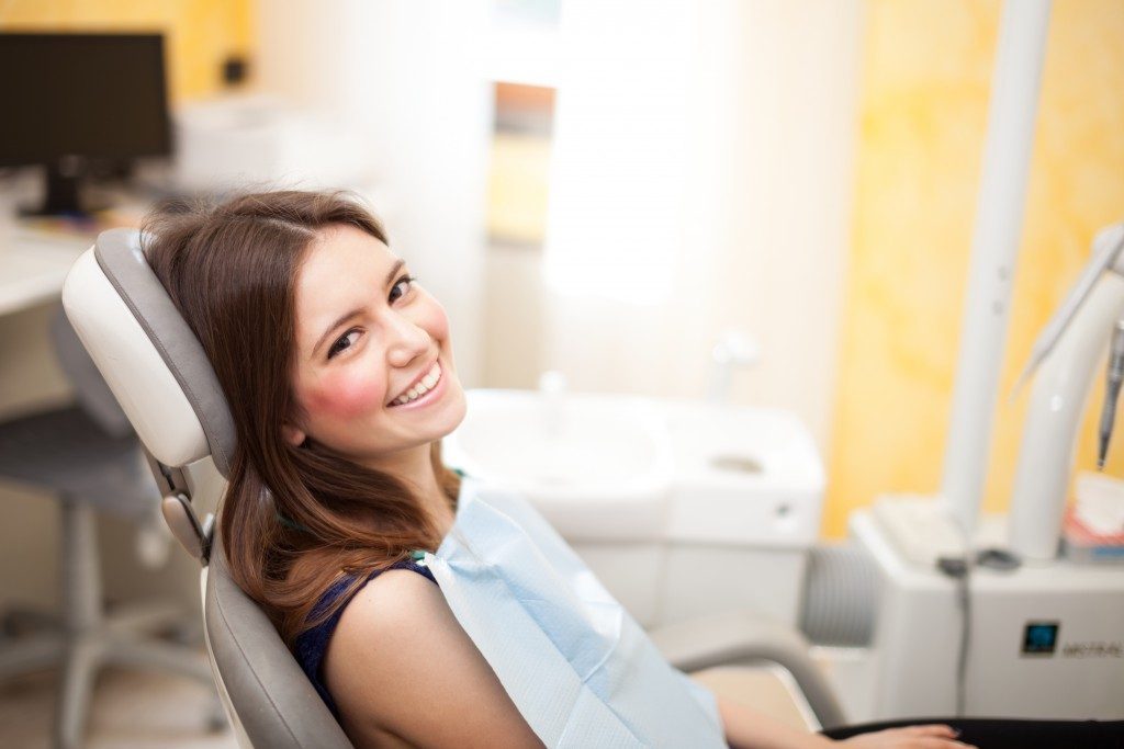 a girl smiling while sitting in a dental chair